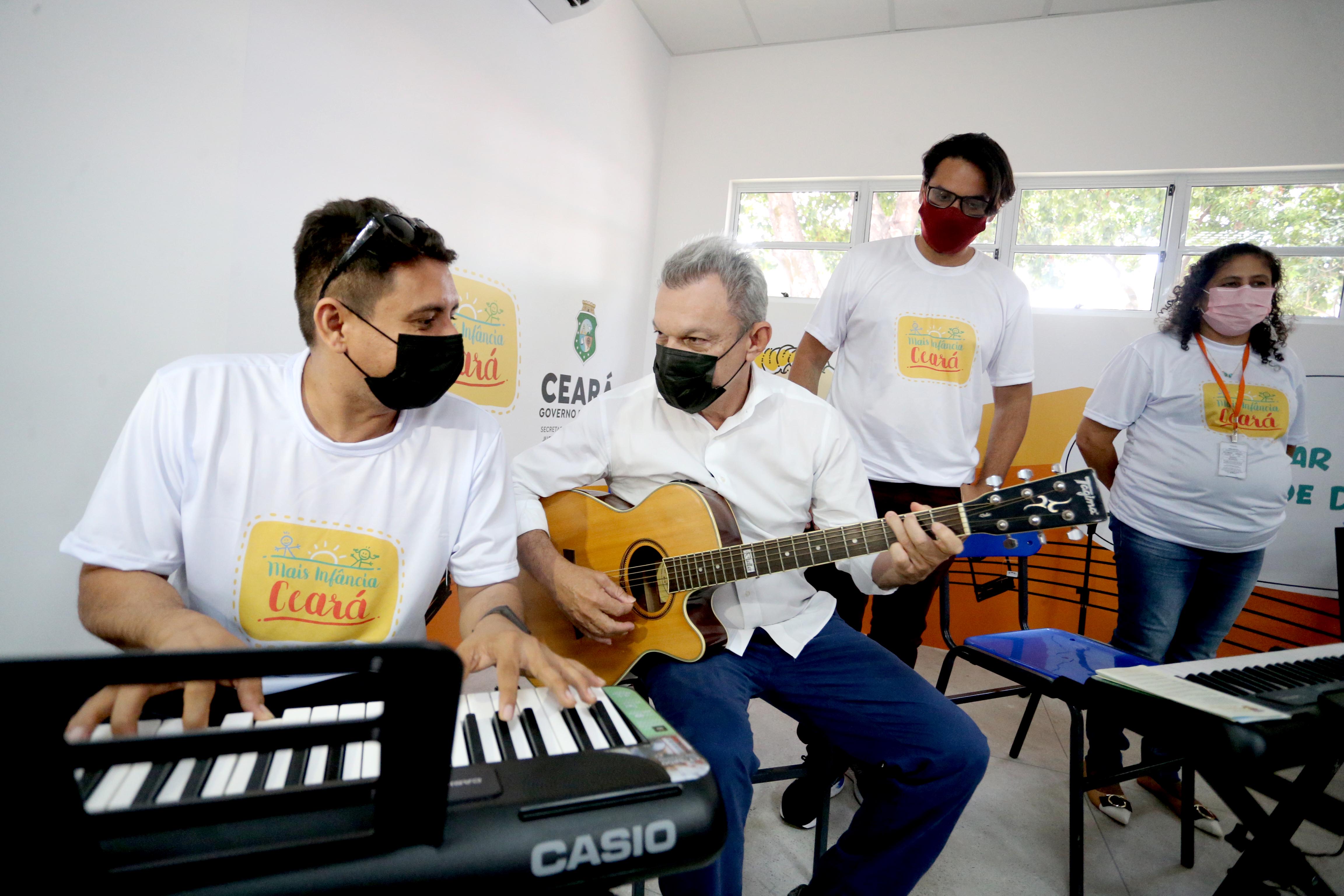 prefeito tocando violão e sendo observado por dois adolescentes